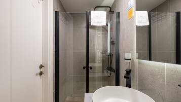 A modern bathroom with a glass-enclosed shower, a white sink, and a mirror.