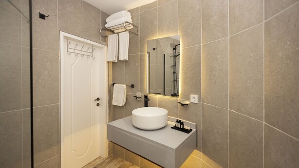 Une salle de bain moderne avec un lavabo blanc, un porte-serviettes et un espace douche.