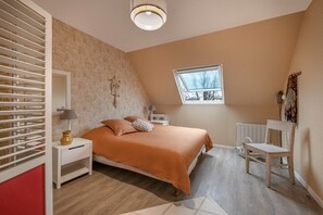 Une chambre à coucher avec un lit, des tables de chevet, une fenêtre et un radiateur.