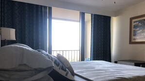 A hotel room with a bed, a window with curtains, a painting on the wall, and a lamp on a bedside table. - Walk To The Beach From This Beautifull New Studio With Everything You Need (St. Thomas)