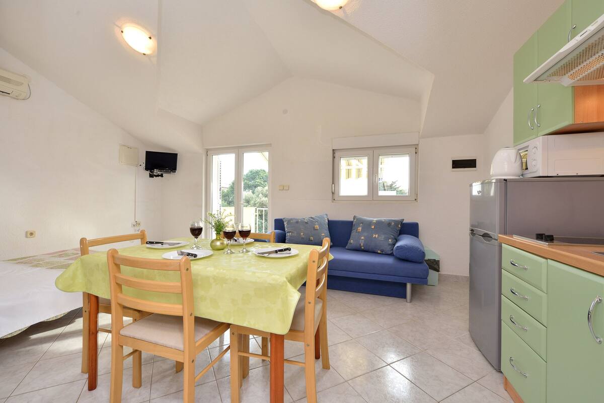 A compact living space with a dining area, kitchenette, and a sofa.