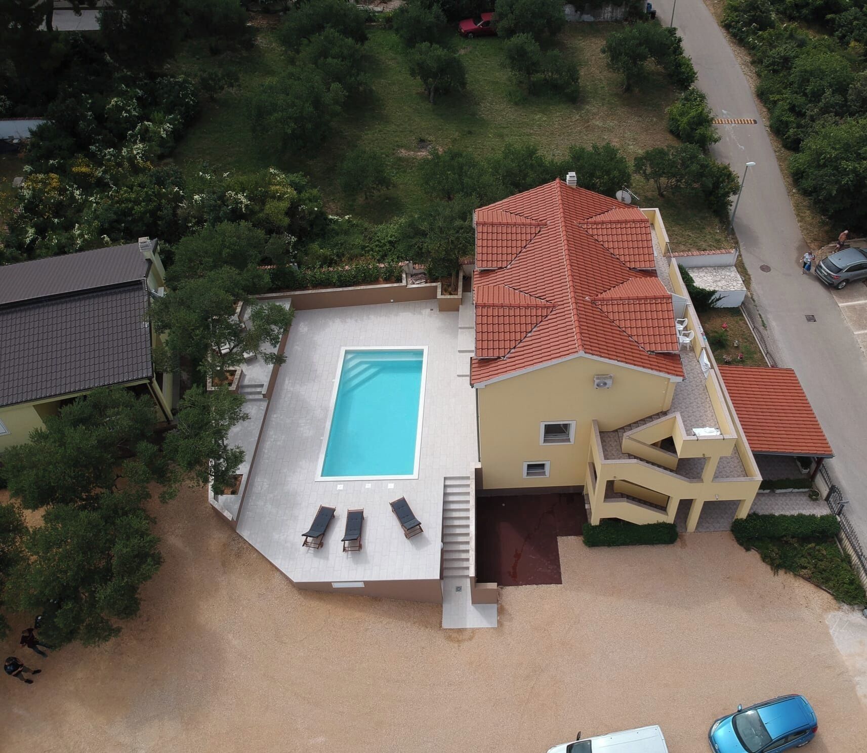 Vista aérea de una propiedad residencial con piscina, terraza cubierta y edificio de dos pisos.