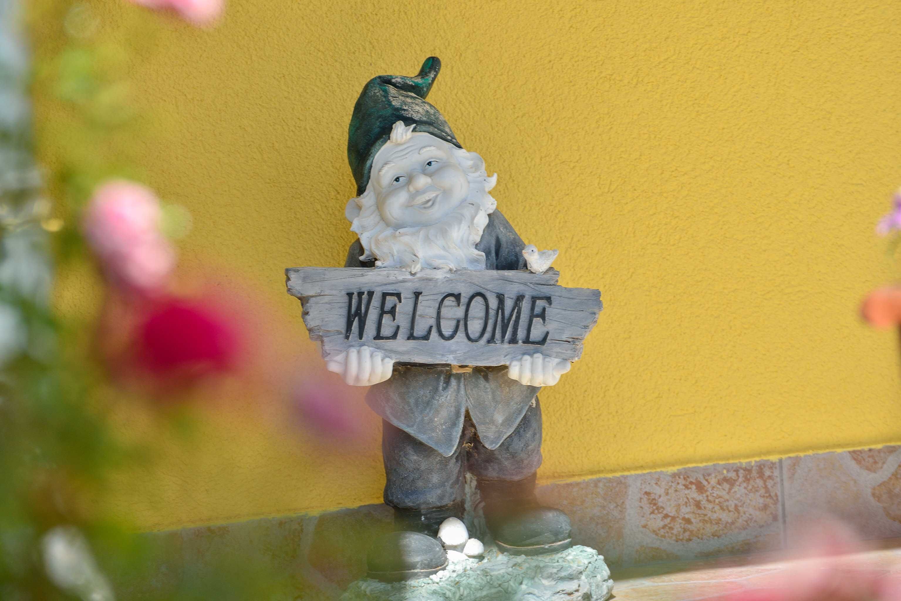 Ein Gartenzwerg mit einem 'WELCOME'-Schild.