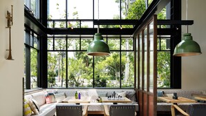 Un rincón cómodo con sofá, sillas y una mesa, con un amplio ventanal que da a vistas de vegetación.