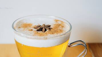 Un vaso de cerveza con espuma y especias sobre una mesa de madera.