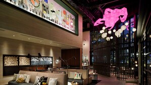 Un lobby moderno con una zona de estar, una gran obra de arte en la pared y una llamativa escultura rosa.
