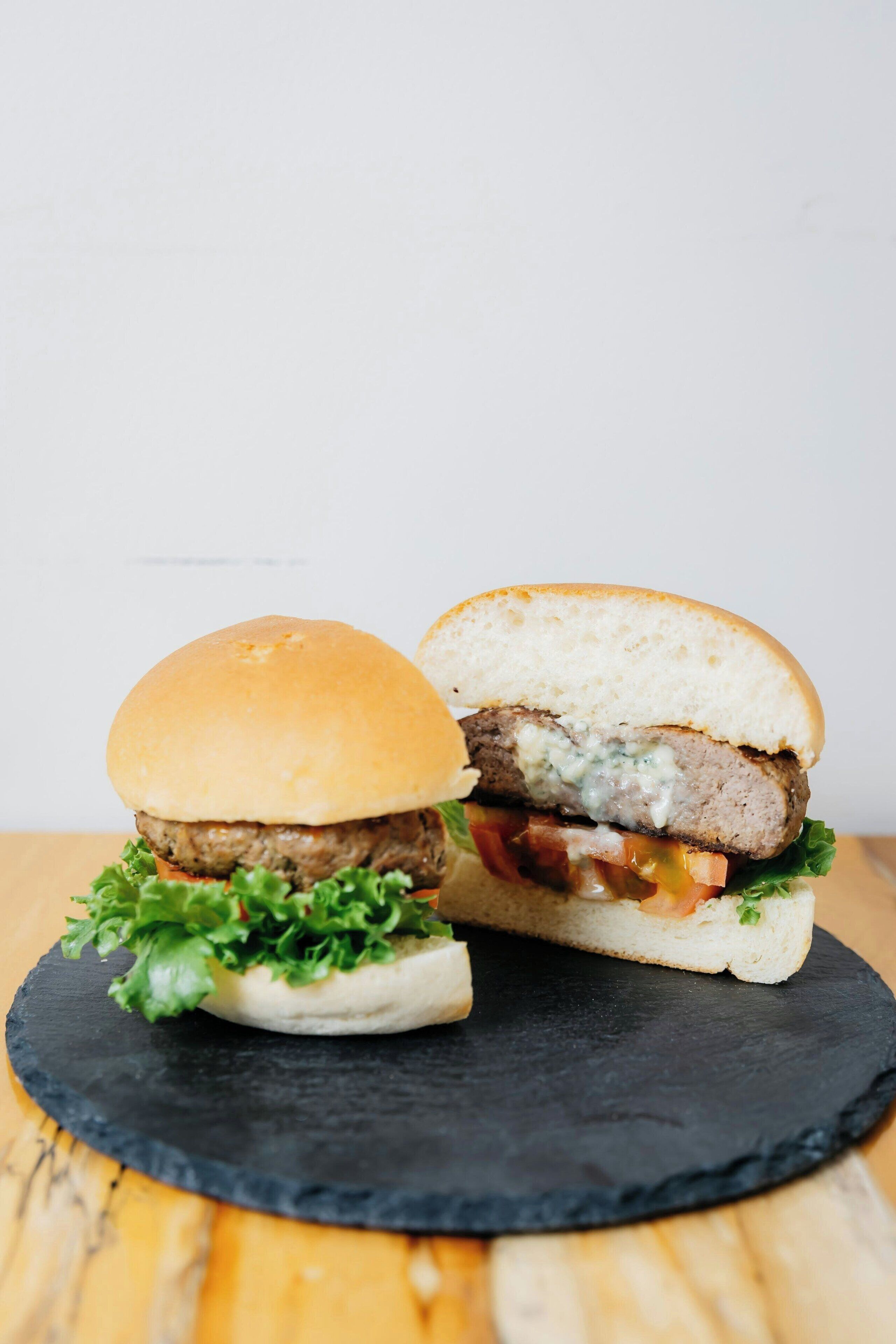 A burger with lettuce, tomato, and a bun on a black slate plate.