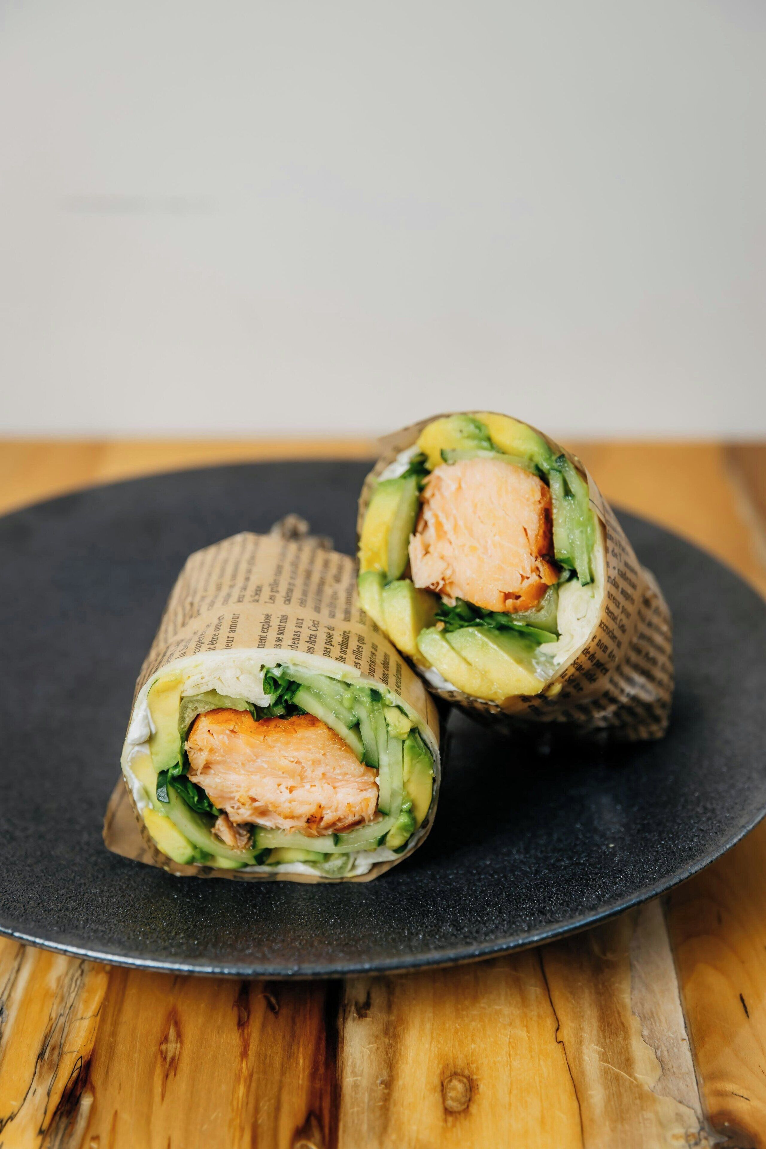 A sushi roll cut in half on a dark plate.