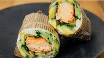 A sushi roll cut in half on a dark plate.