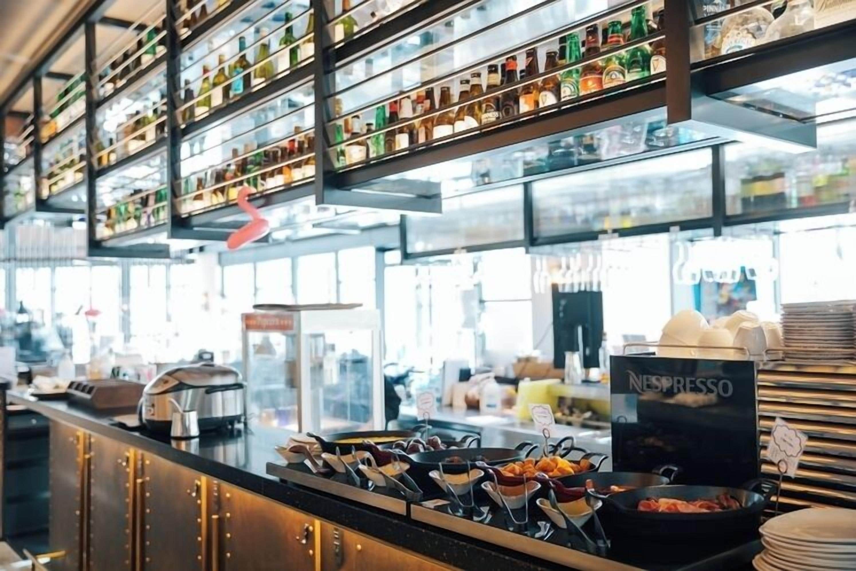 A coffee bar with a Nespresso machine, various coffee pots, and a selection of coffee beans on shelves.