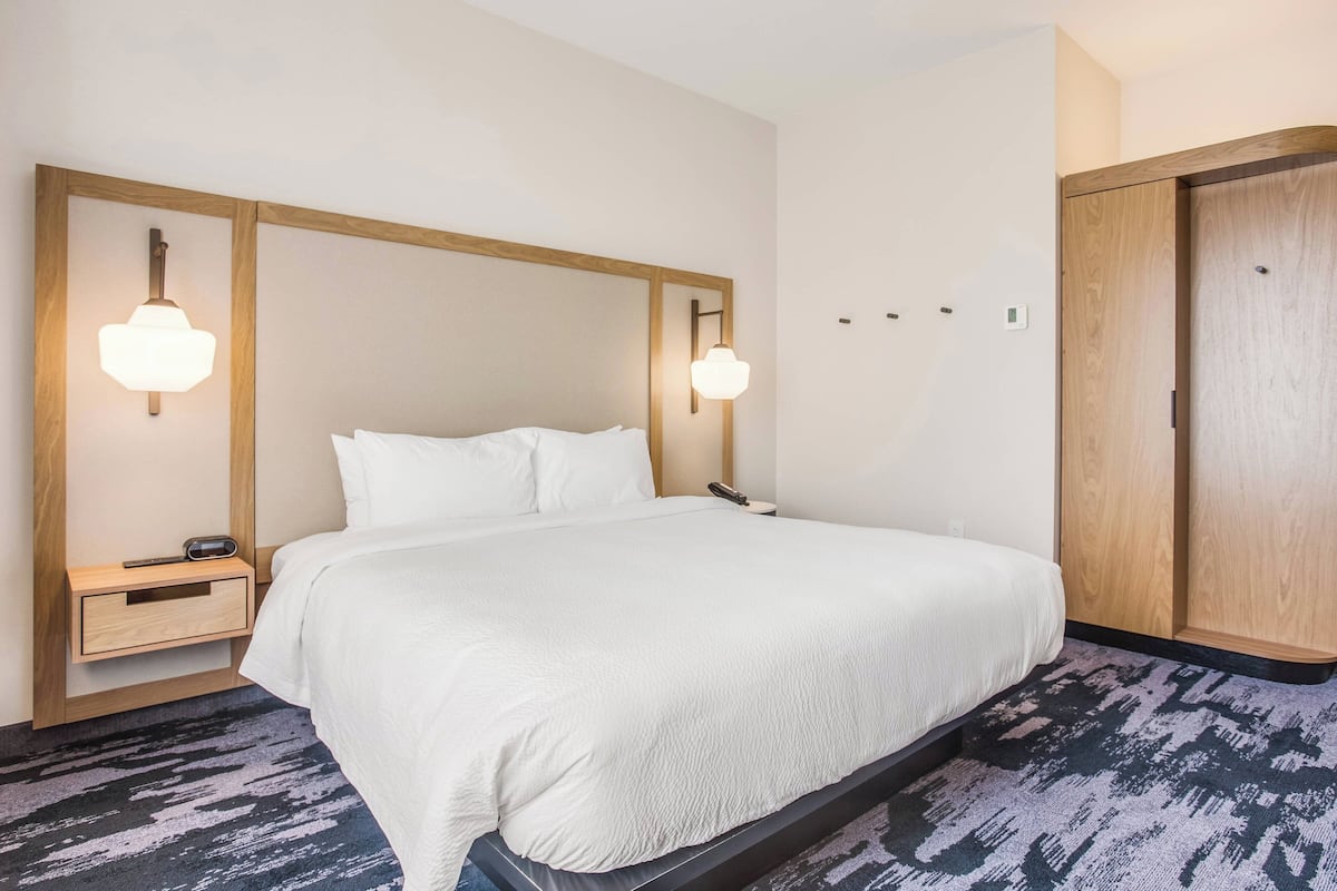 Une chambre d’hôtel dotée d’un grand lit, de tables de chevet, d’une armoire et d’un éclairage mural.