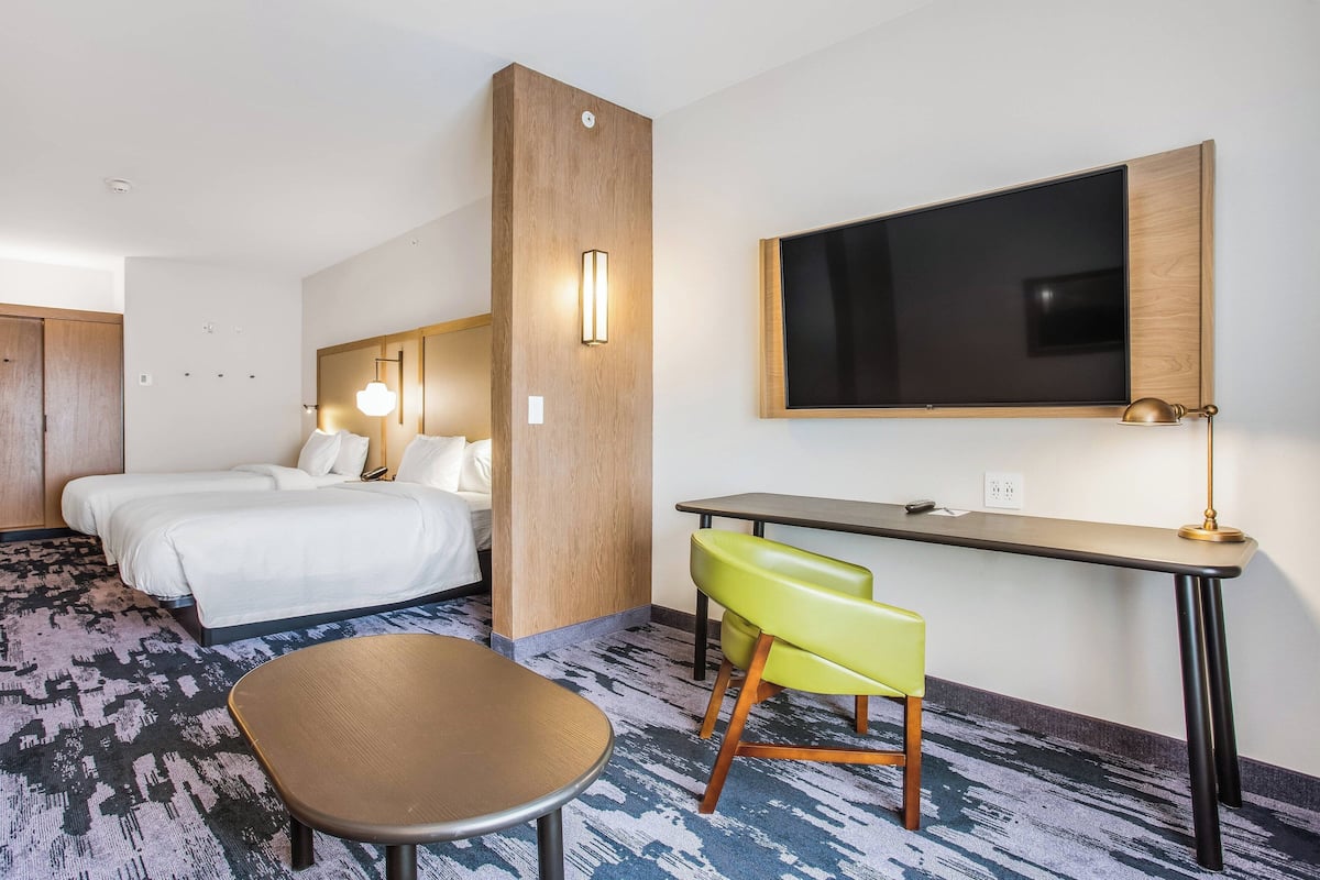 Une chambre d’hôtel avec un lit, un bureau, une chaise et un téléviseur.
