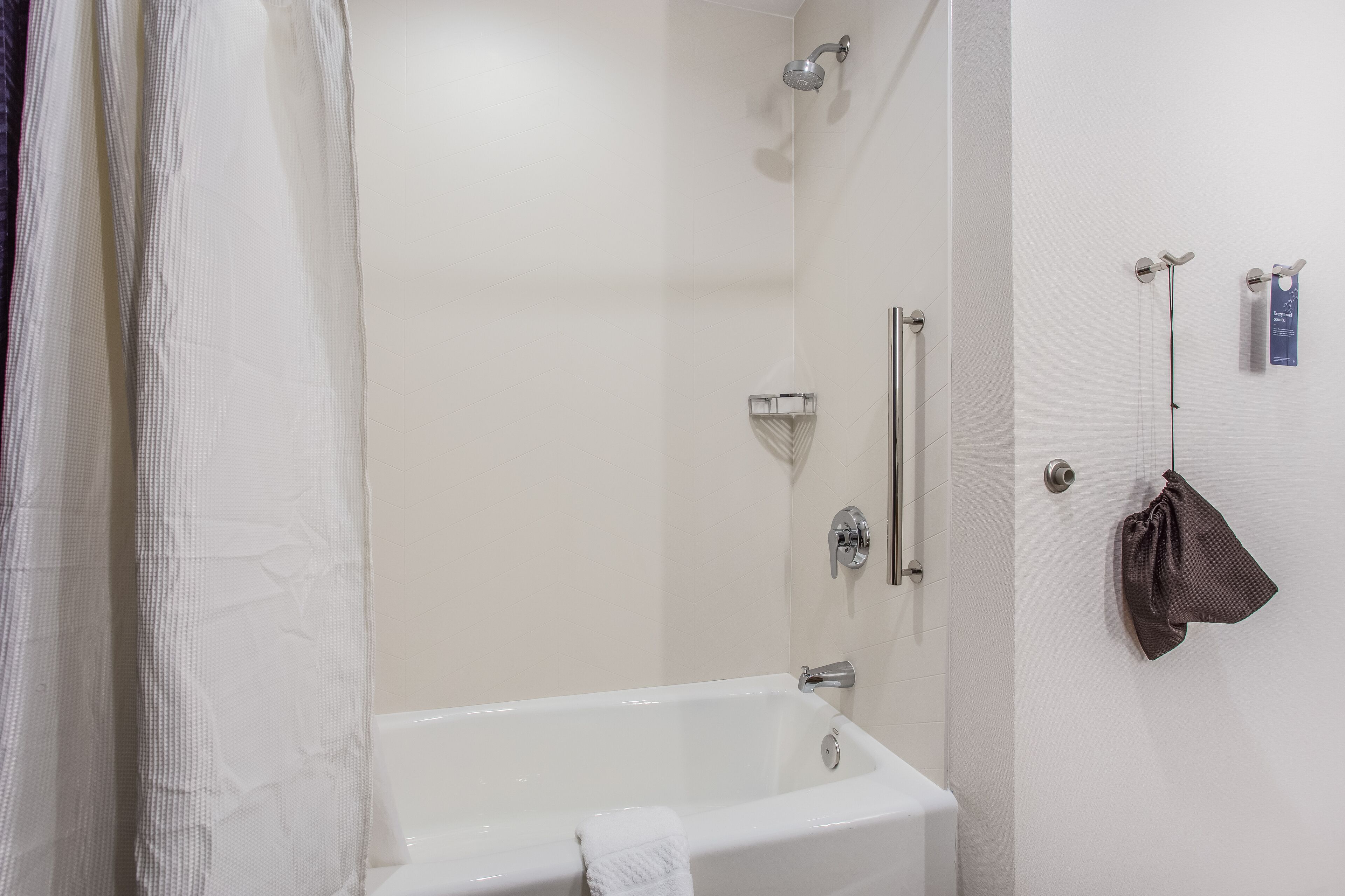 A modern bathroom with a bathtub, shower, and towel rack.