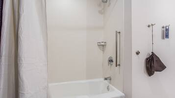 A modern bathroom with a bathtub, shower, and towel rack.
