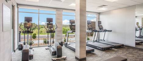 A gym with treadmills, elliptical machines, and a bench.