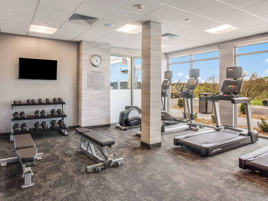 Un gimnasio con cintas de correr, bancos de pesas y mancuernas.