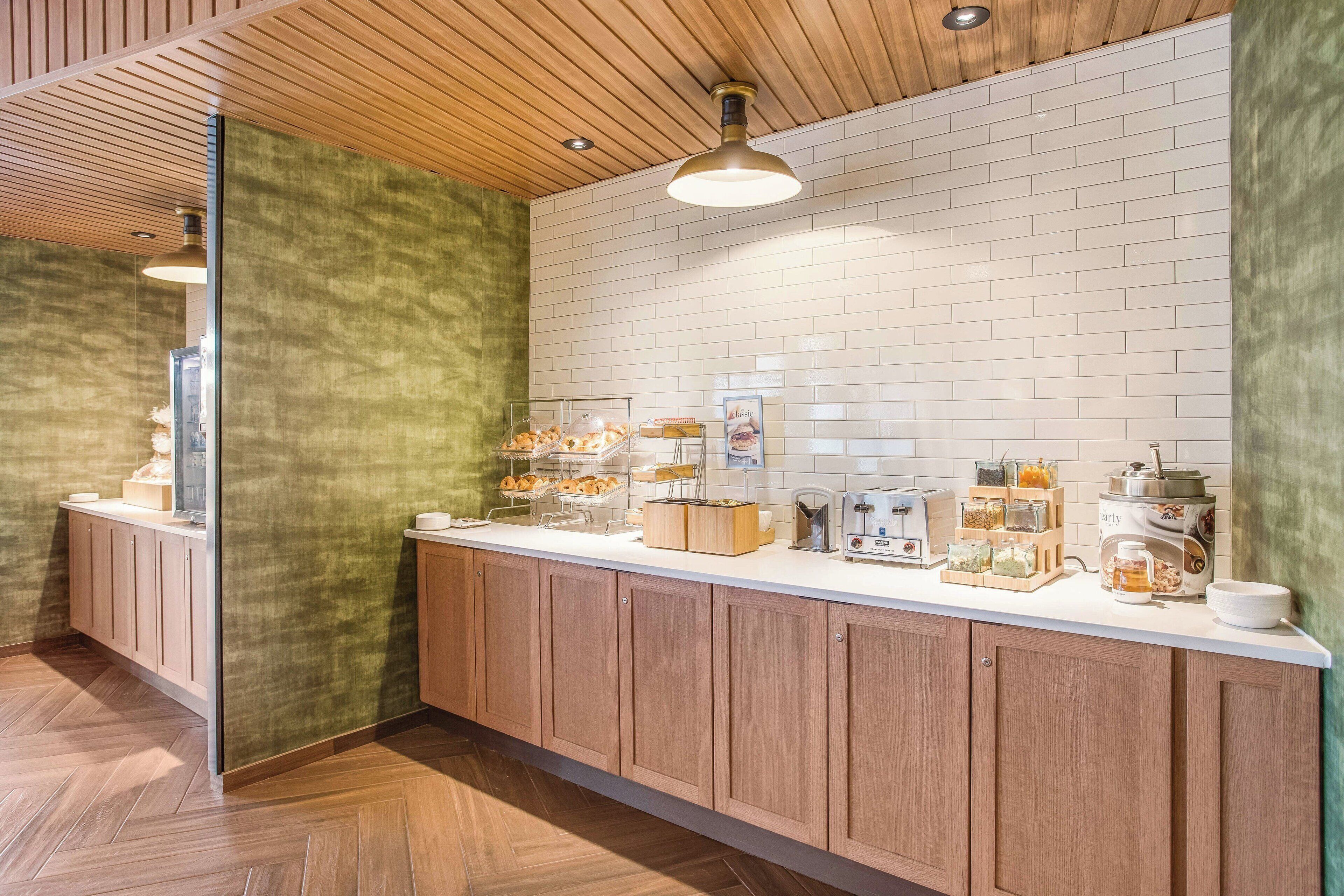 A modern kitchen with wooden cabinets, a white countertop, and various breakfast items.