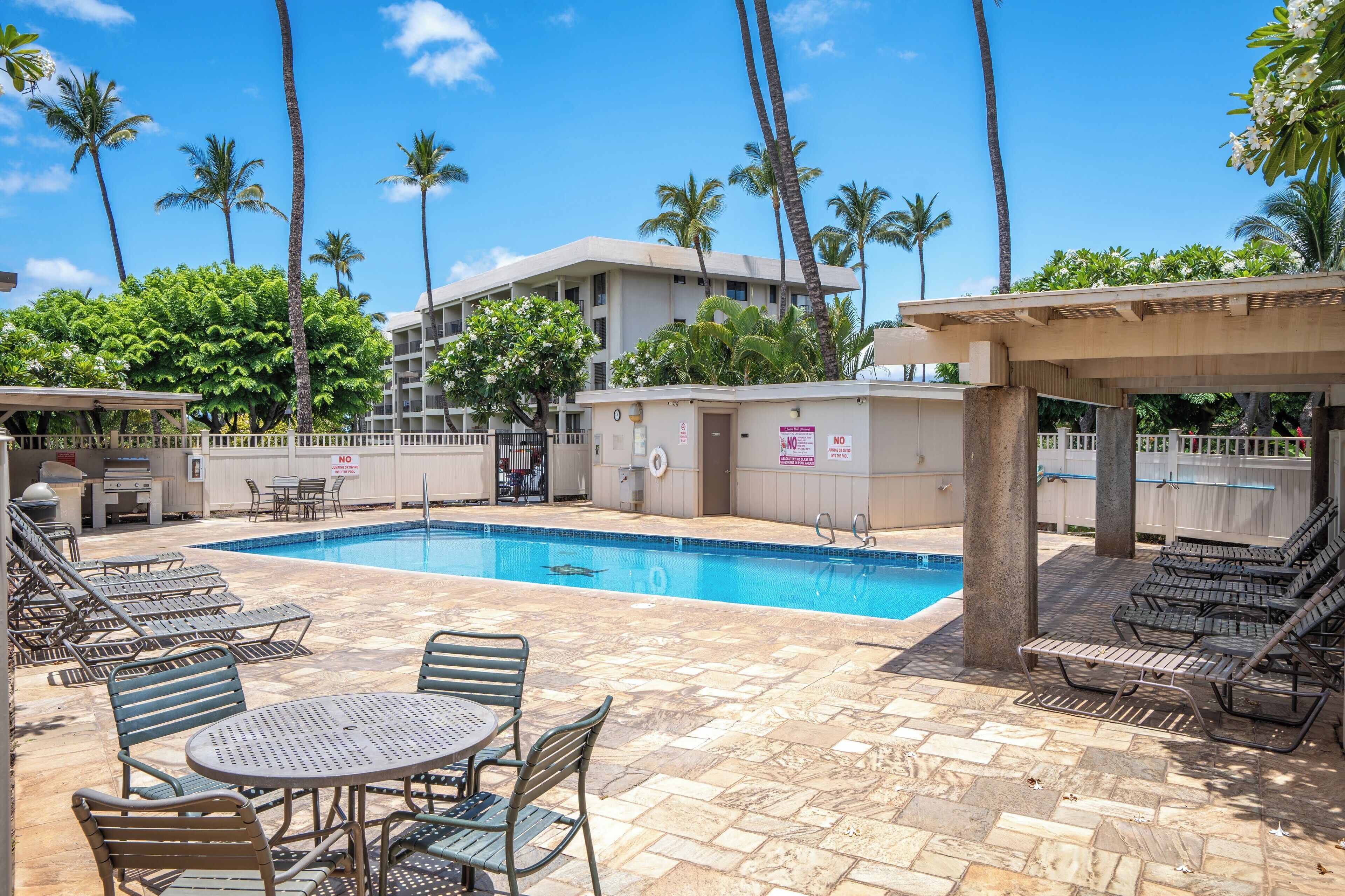 A pool area with lounge chairs, a table, and a pool.