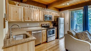 Une cuisine dotée de meubles en bois, d’un plan de travail en granit, d’appareils électroménagers en acier inoxydable et offrant une vue sur l’extérieur.