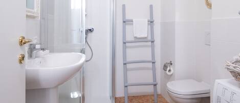 A compact bathroom with a sink, toilet, and shower.