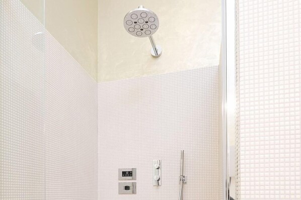 Une salle de bain moderne équipée d’une pomme de douche, d’un panneau de commande et d’un flexible de douche.