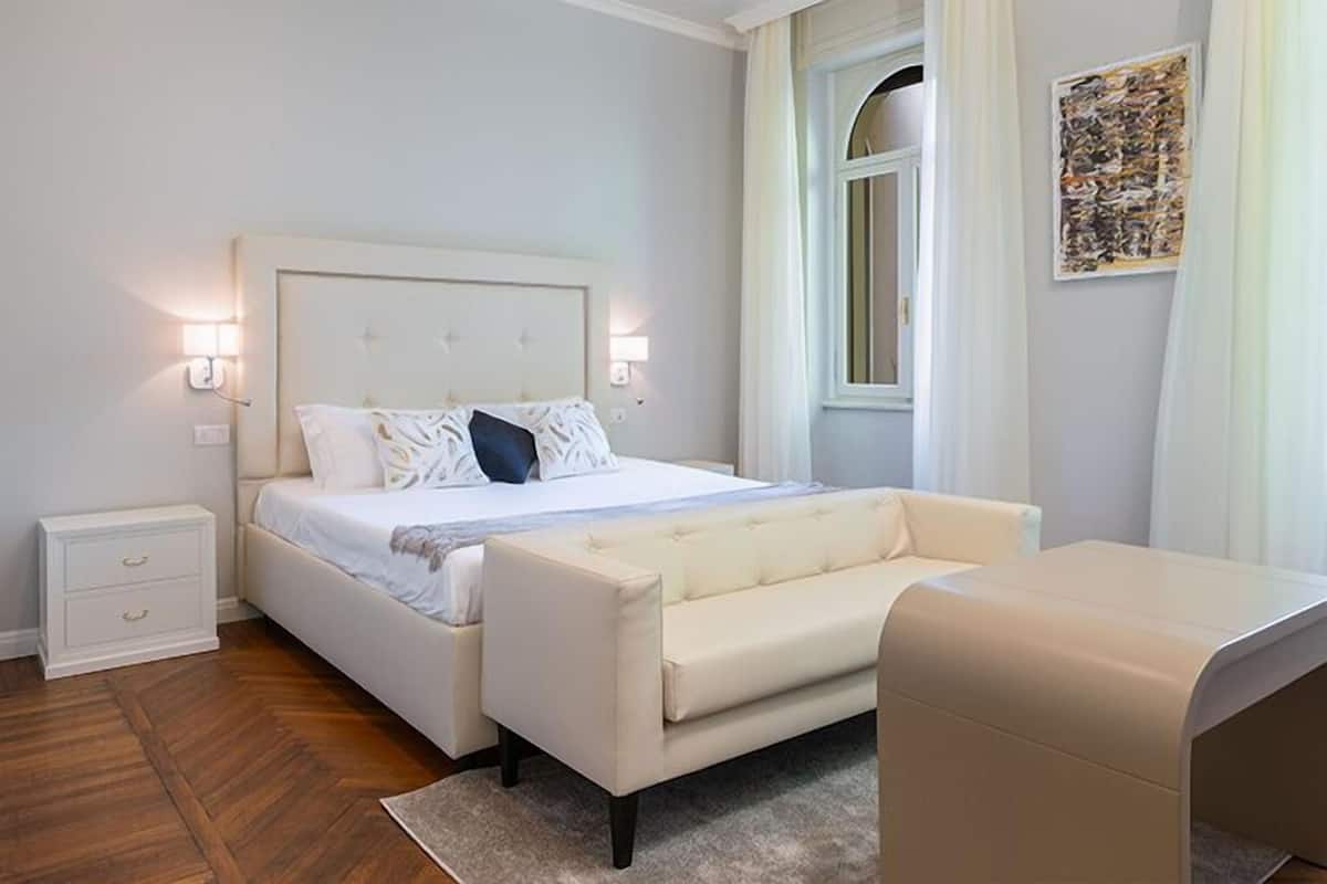 Een slaapkamer met een bed, nachtkastjes, een bank en een raam.
