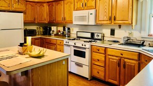 A kitchen with wooden cabinets, a stove, microwave, and a sink. - Charming Farmhouse - quiet, private & peaceful  (Worthington)