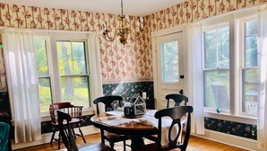 A dining room with a wooden table and chairs, floral wallpaper, and large windows. - Charming Farmhouse - quiet, private & peaceful  (Worthington)