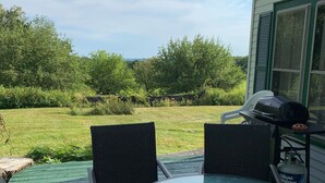 A patio with a round glass table and two chairs, a grill, and a bottle of Blue Moon beer. - Charming Farmhouse - quiet, private & peaceful  (Worthington)