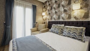 Un dormitorio con cama, una silla, una lámpara de pared y una ventana con cortinas.