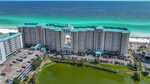 Um hotel de vários andares com um pátio central, estacionamento e vista para o oceano.