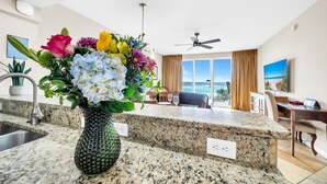 Cozinha moderna com bancadas de granito, um vaso de flores e uma área de refeições com vista.