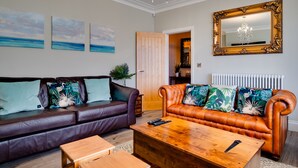 A living room with two leather sofas, a wooden coffee table, and artwork on the wall. - The Station Lodge, Filey. Sleeps 12 (Filey)