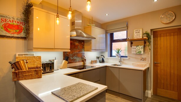 A modern kitchen with white countertops, stainless steel appliances, and pendant lighting. - The Station Lodge, Filey. Sleeps 12 (Filey)