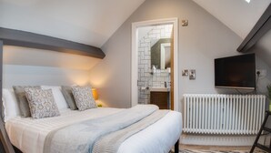 A bedroom with a bed, a TV, a radiator, and a bathroom visible through an open door. - The Station Lodge, Filey. Sleeps 12 (Filey)