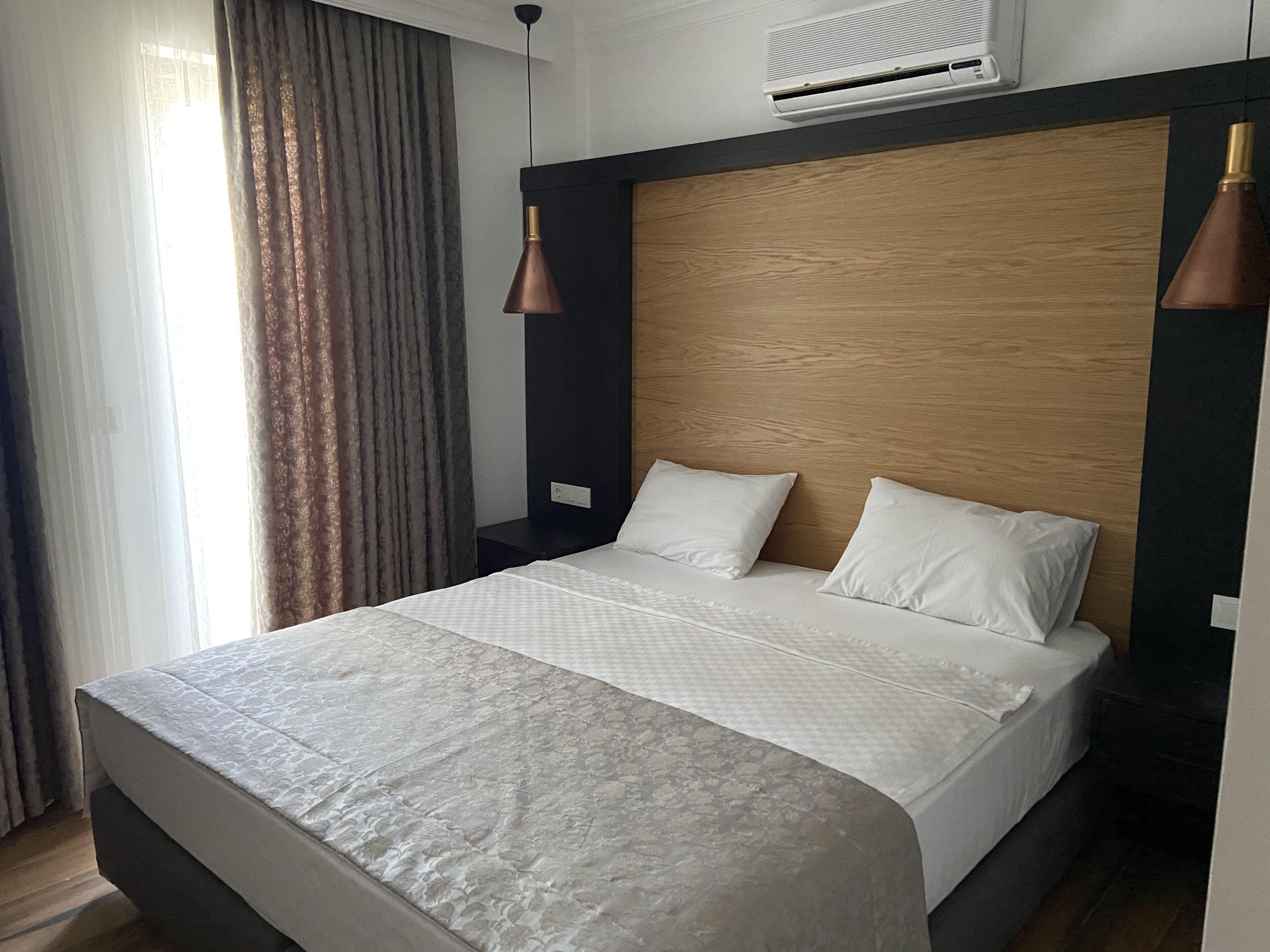 Ein modernes Hotelzimmer mit einem großen Bett, einem Holz-Kopfteil und Pendelleuchten.