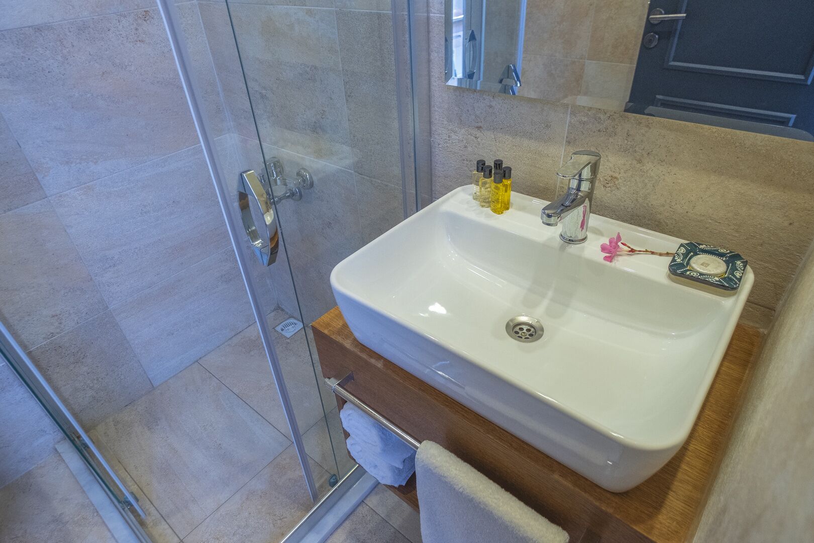 Un baño con lavamanos blanco, un espejo y una cabina de ducha de vidrio.