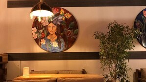 A wooden bed with a headboard, a hanging lamp, a wall-mounted circular painting, and a potted plant. - On Oda Oludeniz (Fethiye)