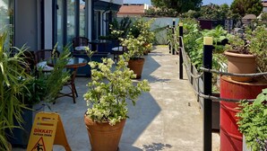 A rooftop terrace with potted plants, outdoor seating, and a wet floor caution sign. - On Oda Oludeniz (Fethiye)