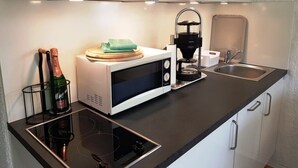 A modern kitchen with a microwave, coffee maker, and a bottle of champagne. - Breitkopf vacation apartment with south-facing terrace and mountain view (Reit im Winkl)