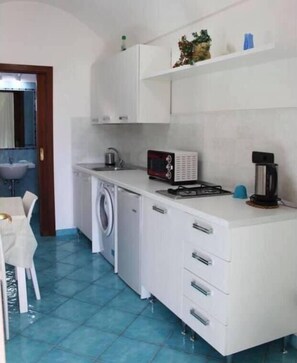 Compact kitchen area with a washing machine, microwave, and dining table.