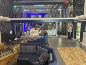 A hotel lobby with a reception desk, seating area, and a staircase leading to an upper level. - Motel 6 Duluth, GA- Atlanta- Gwinnett Place (Duluth)