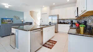 A modern kitchen with white cabinets, stainless steel appliances, and a granite countertop.