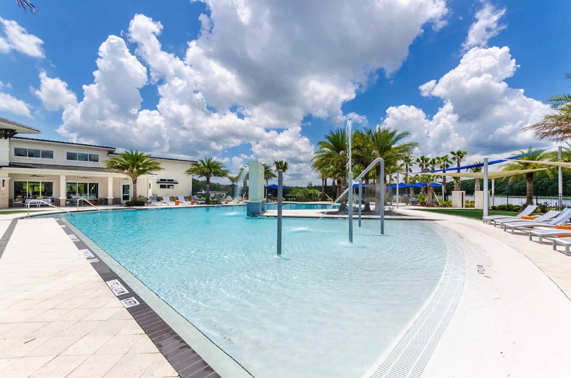 A swimming pool with clear blue water, surrounded by lounge chairs and palm trees.