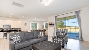 A modern living room with a grey sofa, a patterned armchair, and a leather ottoman.