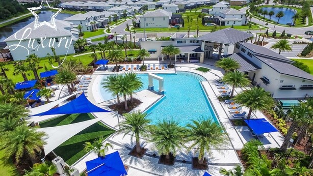 A luxury resort with a large central pool, multiple smaller pools, and a well-maintained landscape with palm trees and blue canopies.