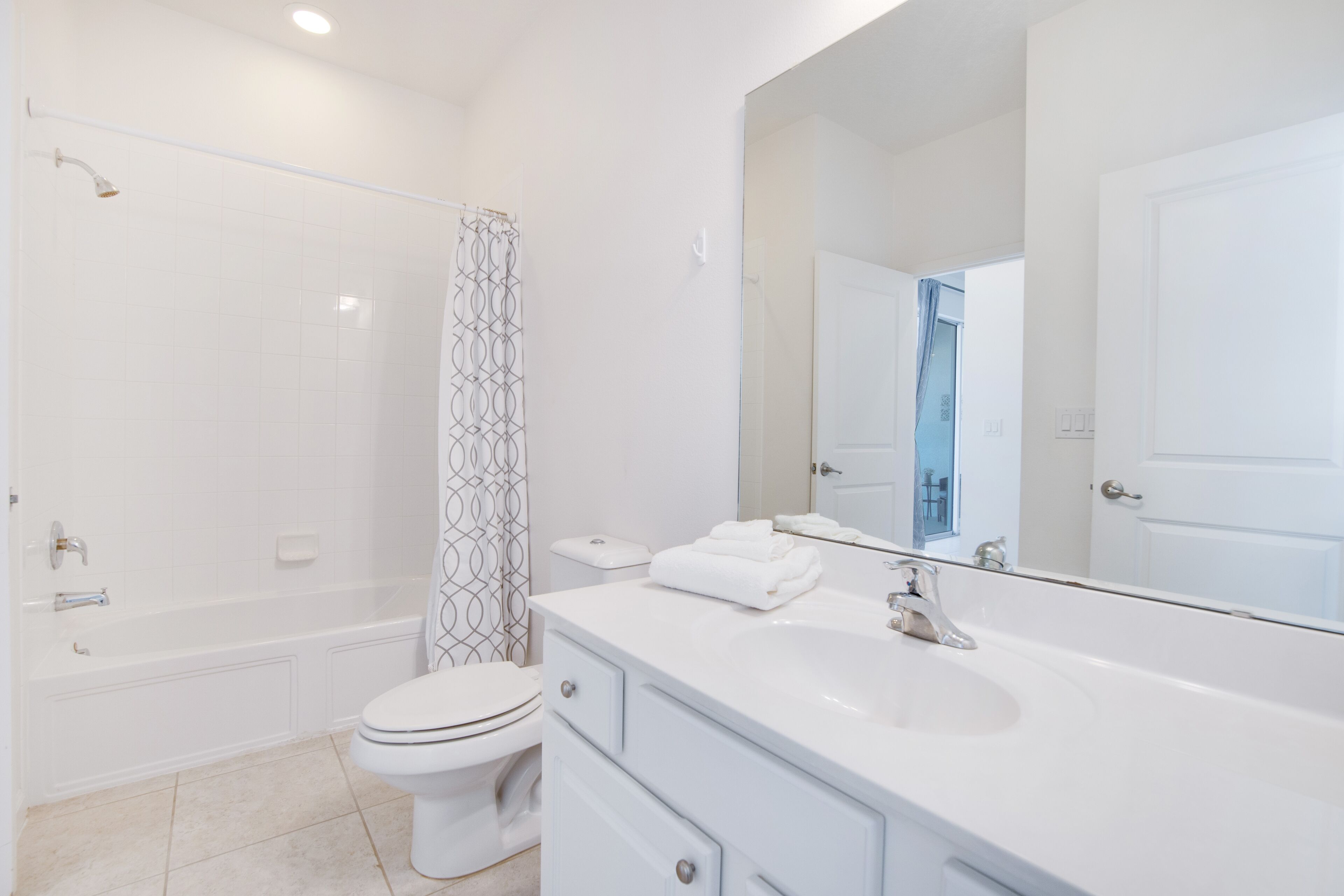 A modern bathroom with a bathtub, toilet, and a large mirror.