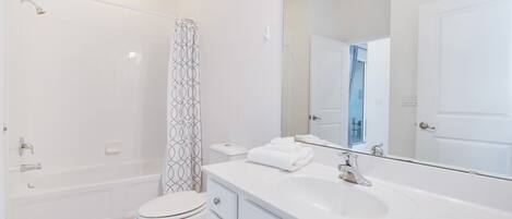 A modern bathroom with a bathtub, toilet, and a large mirror.