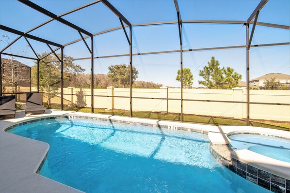 A swimming pool with a covered area, clear blue water, and a view of the surrounding landscape.