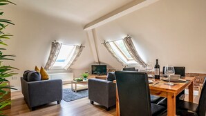 Un loft modern amb zona de menjador, dos sofàs, un televisor i taula de dinar amb cadires.